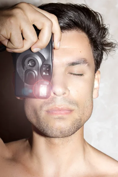 A man photographs himself in the mirror on an old film camera with flash
