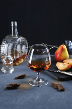 çikolata ve armut ile bir bardak konyak. Bir kap içinde kaldırıldı ve kapak ile brendi