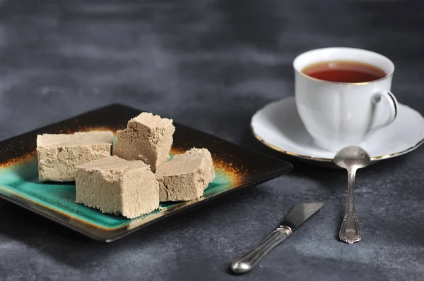 Halva Cortado Fatias Uma Chapa Chá Uma Caneca Fundo Escuro — Fotografia de Stock