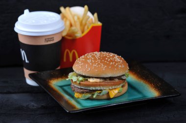 St.Petersburg, Rusya Federasyonu - 12 Ağustos 2018: Mcdonald's yemek rutic siyah arka plan üzerinde içerir Big Mac, patates kızartması, kahve fincanı