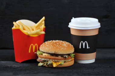 St.Petersburg, Rusya Federasyonu - 12 Ağustos 2018: Mcdonald's yemek rutic siyah arka plan üzerinde içerir Big Mac, patates kızartması, kahve fincanı.