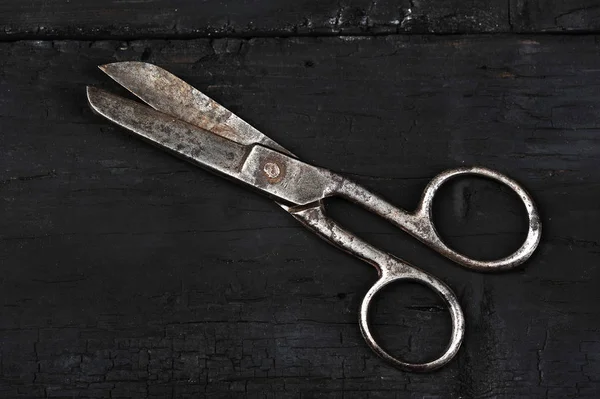 Old vintage scissors on wooden black coal background