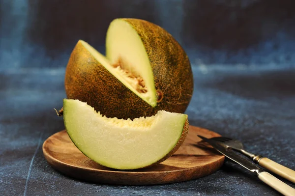 melon cut in half and into pieces on wooden board