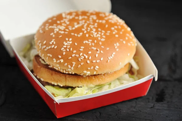 Burger in a red box with a bun with sesame seeds close-up