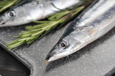 bir kesme tahtası üzerinde rosemary ile ham saury