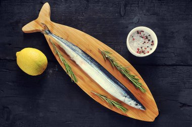 Biberiye ve limon-Tepe Manzaralı balık şeklinde ahşap bir tahta üzerinde ham saury