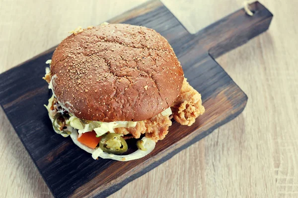 Burger with dark bread to a wooden Board with roasted chicken top view