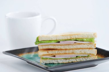 bir plaka üzerinde jambon, peynir ve salata sandviç