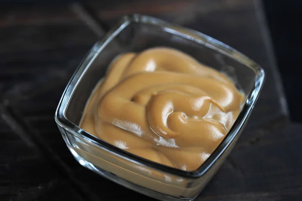 Mustard in a glass dish on a dark wooden background — Stock Photo, Image