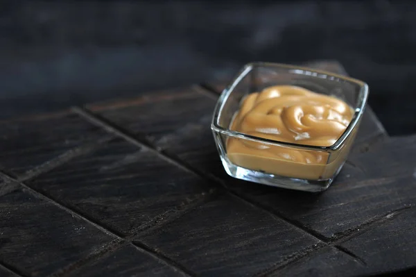 Mustard in a glass dish on a dark wooden background — Stock Photo, Image