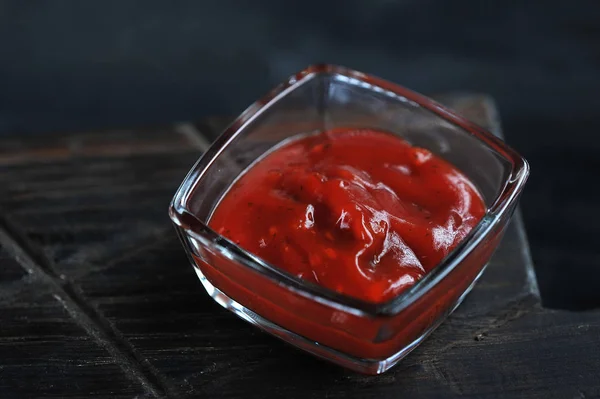 Ketchup in piatto di vetro su fondo di legno scuro — Foto Stock