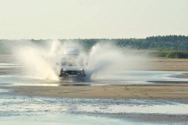Rus araba Niva unde gelen sıçramaları ile bir kıyı yolunda sürmek