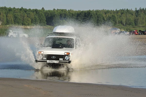 Voiture russe Niva monte sur une route côtière avec des éclaboussures de Unde — Photo