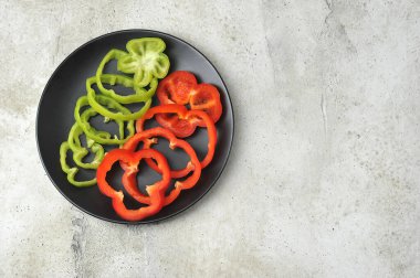 yeşil ve kırmızı biberler siyah bir plaka üzerinde halkalara bölünmüş - üst görünüm - boşluğu kopyala