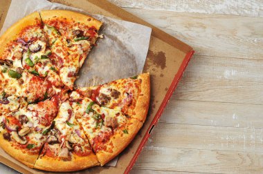 Et biberli pizza beyaz arka planda karton ambalajda duruyor, yakın plan üst görünümde.