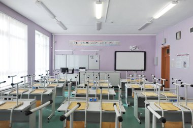 Öğrenci olmayan sınıf - çalışma masaları ve devrilmiş sandalyeleri olan eğitim sınıfı 1 Eylül için hazır - okula geri dönüyor