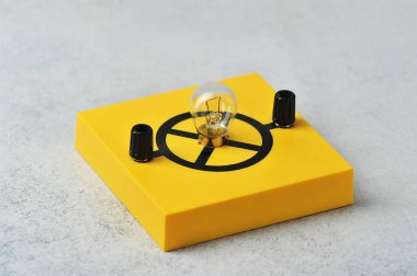 Sarı bir standın üzerinde parlak bir lamba - fizik dersi için ekipman - parlak lamba unvanına sahip cam ampul