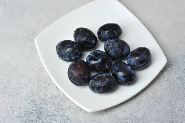 juicy ripe black and blue plums on a plate