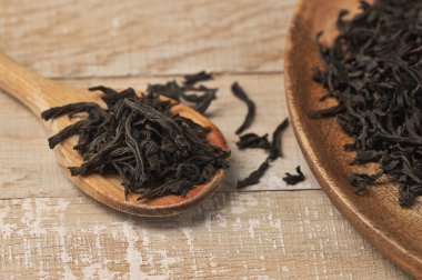 Tahta kaşıkta siyah yaprak çayı ve ahşap arka plan