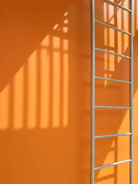 垂直フレーム内のオレンジの建物の外の火災脱出の表面上のバラスタの日光と影 — ストック写真