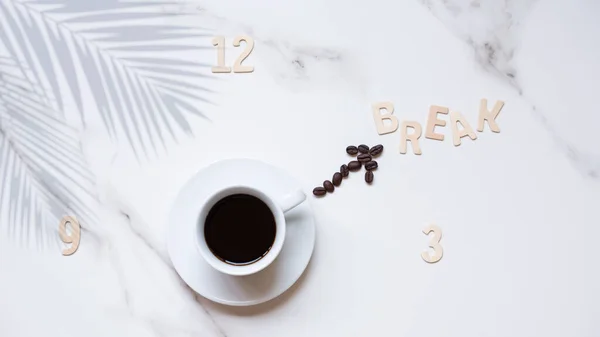 Flat lay of black coffee in white ceramic cup and coffee beans line in clock hand shaped with wooden numbers and \