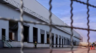 Önünde bulanık çelik çit olan büyük dağıtım deposuna odaklan, iş endüstrisi konseptinde güvenlik