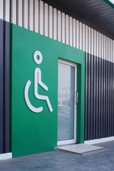 Biały Znak Niepełnosprawnych Wózków Inwalidzkich Szklanymi Drzwiami Zielonej Ścianie Drewnianymi — Zdjęcie stockowe