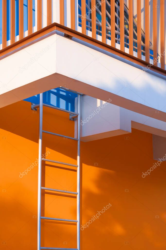 Low angle view of fire escape with safety baluster on colorful building wall in vertical frame