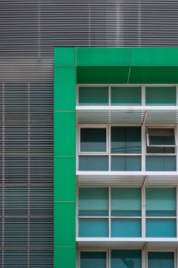 Modern bina duvarı dekorasyonunda yeşil çerçeveli cam pencereler ve dikey çerçevede beyaz yüzgeç