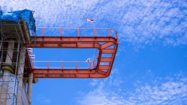 Mavi gökyüzündeki beyaz kabarık bulutlara karşı inşa sırasında büyük Tayland tapınağından uzanan teras yapısının alçak açılı görüntüsü