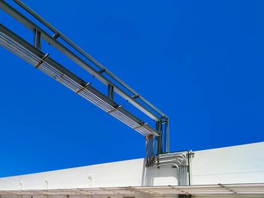 Açık hava gaz boru hatlarının beyaz binaya düşük açılı görünümü mavi berrak gökyüzü arkaplanına karşı