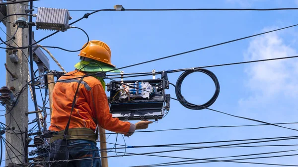 Ahşap merdivendeki teknisyenin arka görüntüsü mavi gökyüzü arka planına karşı fiber optik ve internet ayırıcı kutusu kuruyor