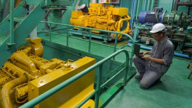 Makine dairesinde çalışan Asyalı mühendis. Balıkçı teknesi, işgali ve teknoloji konseptini kontrol etmek için dizüstü bilgisayar kullanıyor.