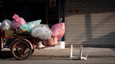 Kullanılmış su şişeleri plastik poşetlerde ve çeşitli geri dönüşümlü atık sabah vakti sokakta eski üç tekerlekli hurda alıcısı motosiklet