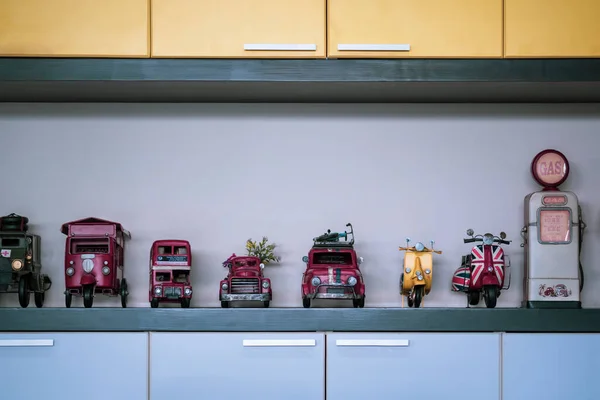 Row of miniature retro vehicle toys with fuel dispenser on  wooden shelf decoration in living room