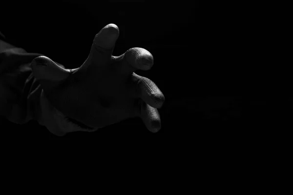 紧紧抓住黑衣神秘罪犯的可怕手 从黑暗的背景中伸出手来 低调而又黑白分明 — 图库照片