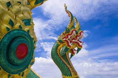 Mavi gökyüzü arka planında beyaz buluta karşı 3 başlı yılan heykelinin alçak açısı ve yan görüntüsü