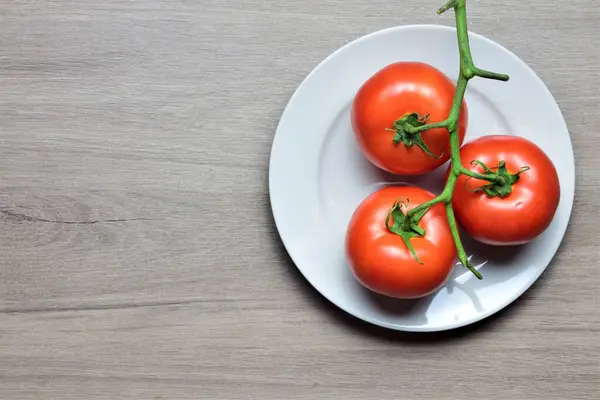 Tomates Vermelhos Ramo Uma Chapa Branca Uma Mesa Madeira Circular — Fotografia de Stock