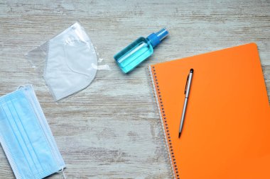 Hava manzarası, ofis veya okul malzemelerinin yanı sıra virüsler, maskeler ve hidro-alkollü jele karşı hijyen malzemesi. Metin için boşluk.