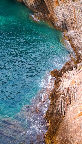 Sarp bir kıyı şeridindeki engebeli kaya oluşumlarına karşı turkuaz deniz suyu turkuazları çarpıcı jeolojik dokuları ve karayla denizin dinamik buluşmasını gözler önüne seriyor..