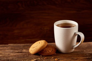 Ahşap ahşap arka plan, üstten görünüm, seçici odak parçası üzerinde çay ve tatlı kurabiye beyaz porselen kupa