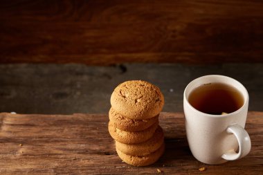 Ahşap ahşap arka plan, üstten görünüm, seçici odak parçası üzerinde çay ve tatlı kurabiye beyaz porselen kupa