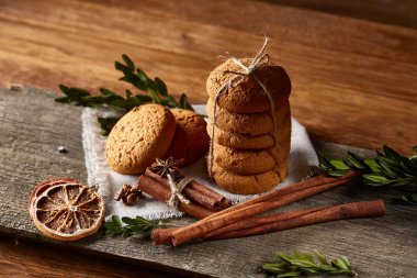 Tanımlama bilgileri, tarçın ve hafif ahşap arka plan üzerinde kurutulmuş portakal yığını ile Noel kompozisyon yakın çekim.