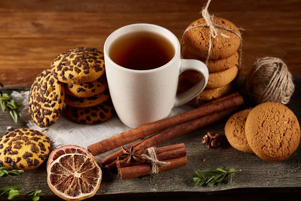 Concepto tradicional de té de Navidad con una taza de té caliente, galletas y decoraciones en una mesa de madera, enfoque selectivo —  Fotos de Stock