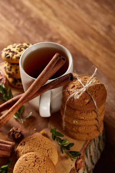 Conceito de Natal com uma xícara de chá quente, biscoitos e decorações em um log sobre fundo de madeira, foco seletivo — Fotografia de Stock