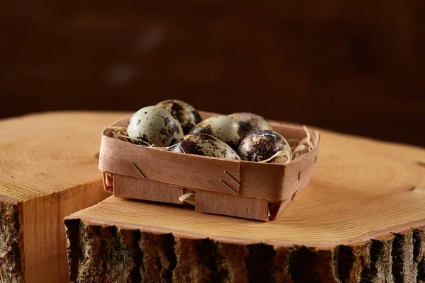 Quail eggs in a box on a round log, top view, selective focus. — Stock Photo, Image