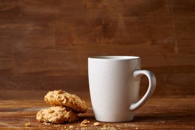 Beyaz porselen kupa çay ve tatlı kurabiye ahşap arka plan, üstten görünüm, seçici odak