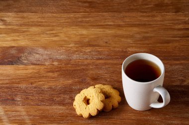 Beyaz porselen kupa çay ve tatlı kurabiye ahşap arka plan, üstten görünüm, seçici odak