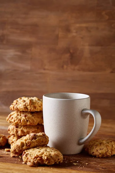 Caneca de porcelana branca de chá e biscoitos doces no fundo de madeira, vista superior, foco seletivo — Fotografia de Stock