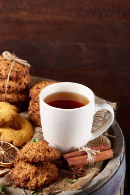 Kavramsal şenlikli bileşimi ile bir fincan sıcak çay, kurabiye ve spicies bir ahşap varil, seçici odak, yakın çekim